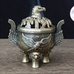 Un majestuoso portaincienso de águila que presenta un tapa con un patrón de nube hueca y un cuerpo adornado con un águila en vuelo en relieve. Este portaincienso de aleación, diseñado con tres patas, simboliza la libertad e independencia, así como la fuerza y el coraje. - Image 6